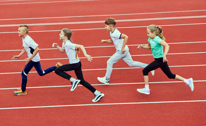 Kinderen die over een atletiekbaan rennen. 